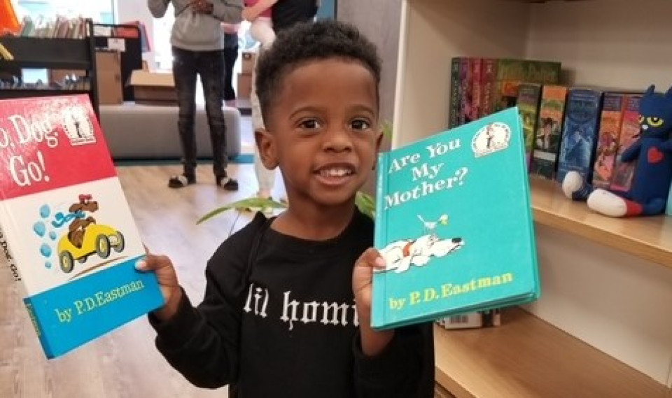 Student athletes standing with child holding hog mollie books