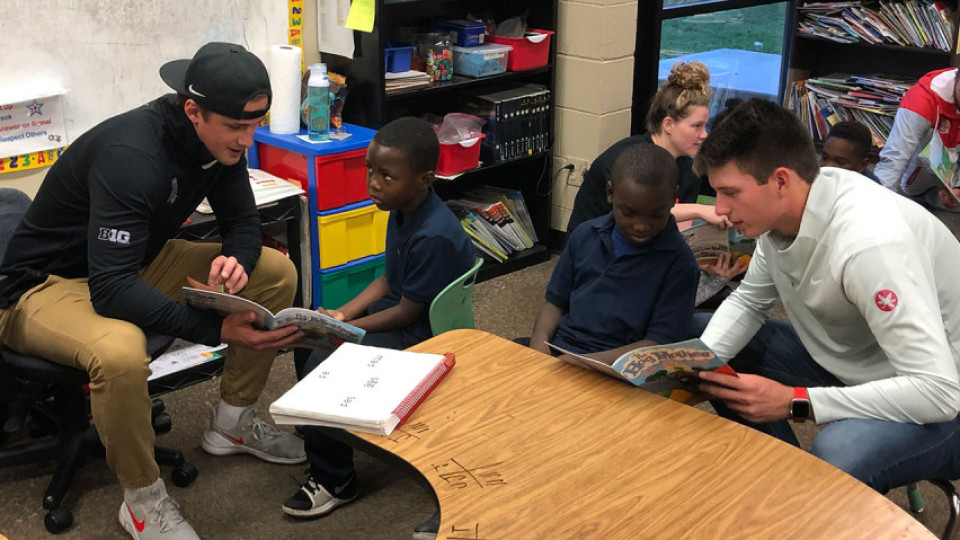 Student athletes reading with children